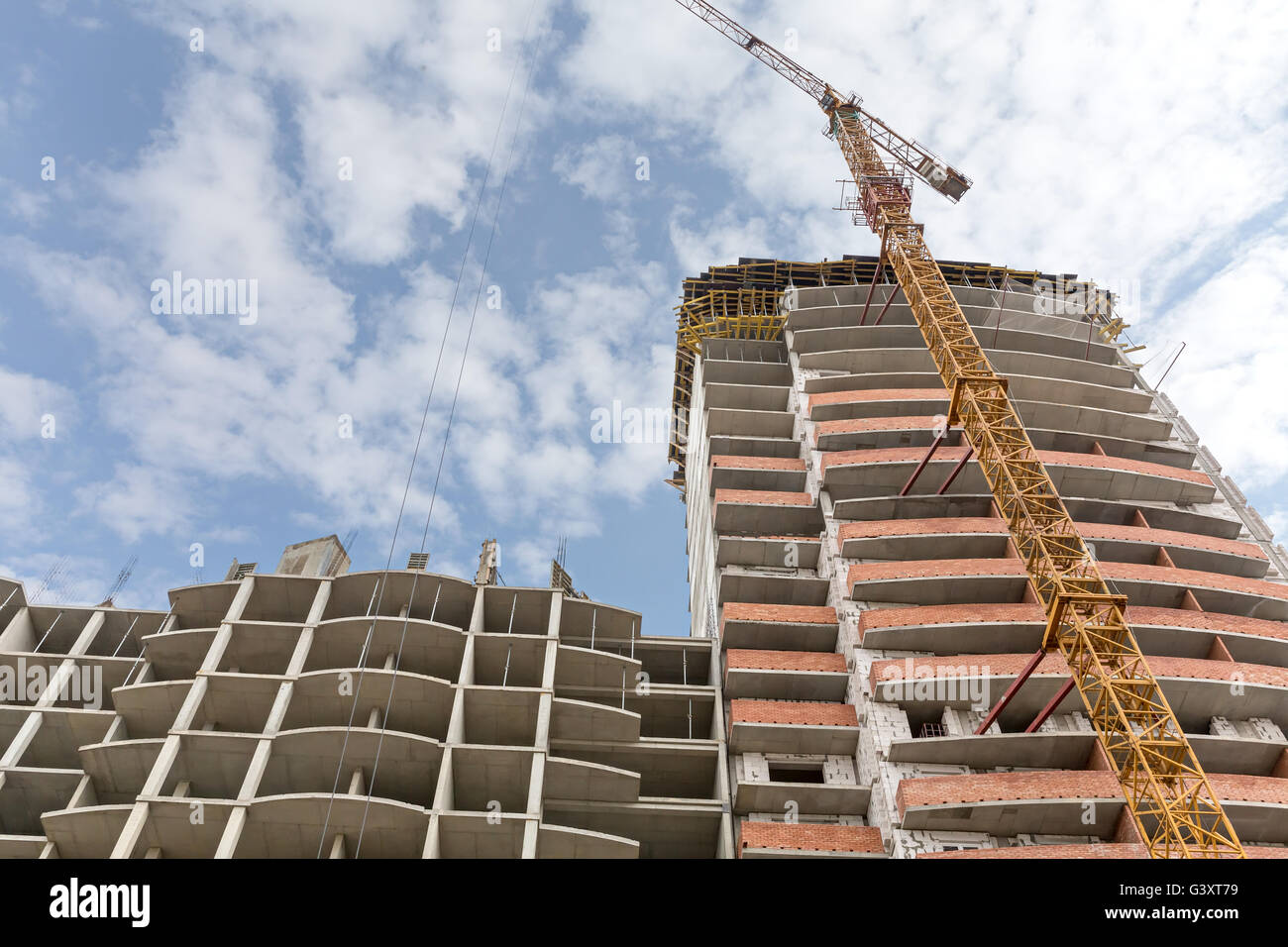 Alto edificio sito in costruzione con giallo gru a torre Foto Stock