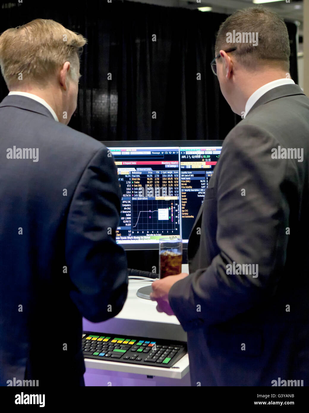 Gli investitori di parlare di fronte allo schermo del computer che mostra l'andamento dei mercati azionari - USA Foto Stock