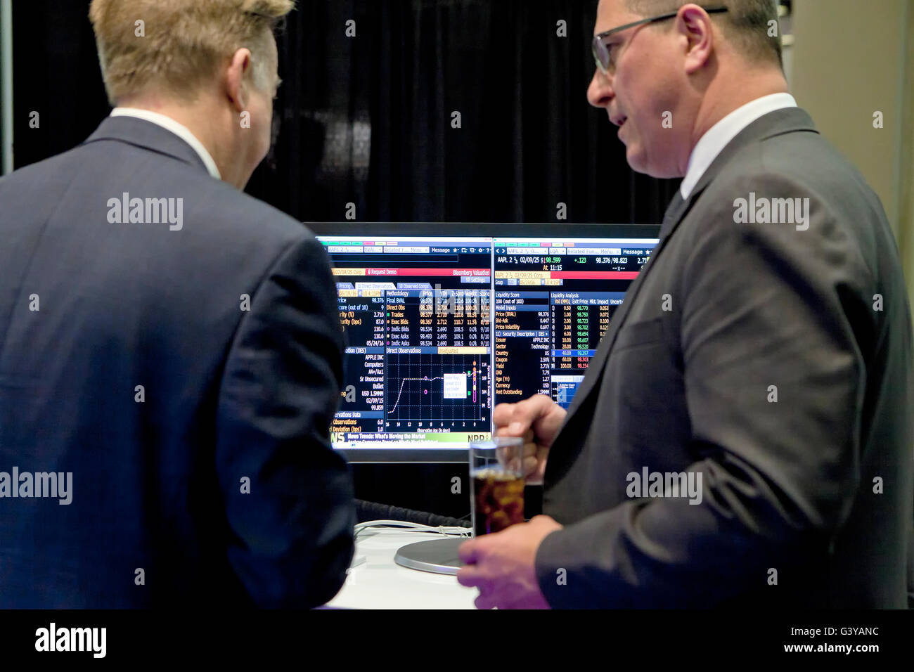 Gli investitori di parlare di fronte allo schermo del computer che mostra l'andamento dei mercati azionari - USA Foto Stock