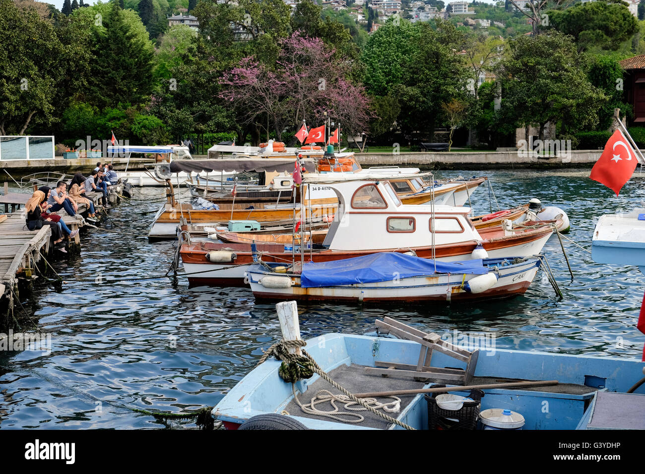 Ormeggiate barche da pesca sul Bosforo in una giornata di sole in Istanbul con persone in appoggio dall'acqua Foto Stock