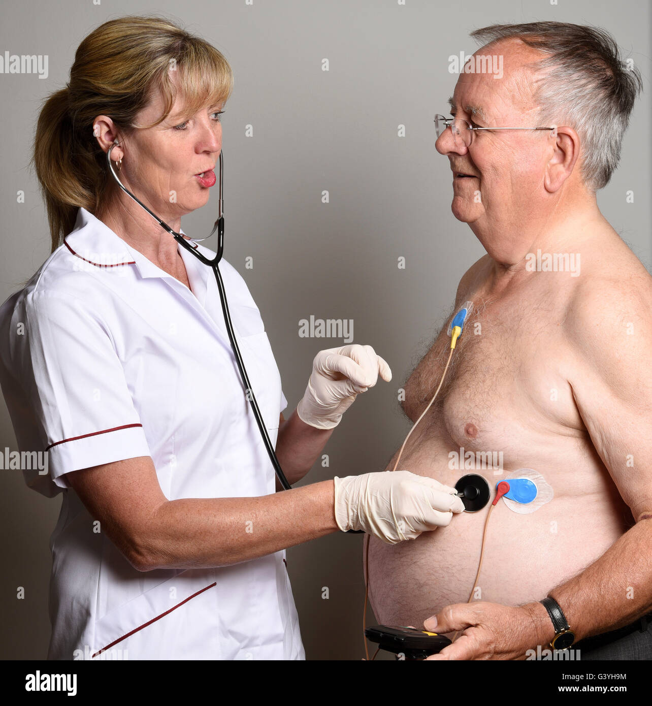 Gli stati di un ospedale di misurazione cardiaca team installando un ambulacro un monitor ECG per un sovrappeso paziente di sesso maschile Foto Stock