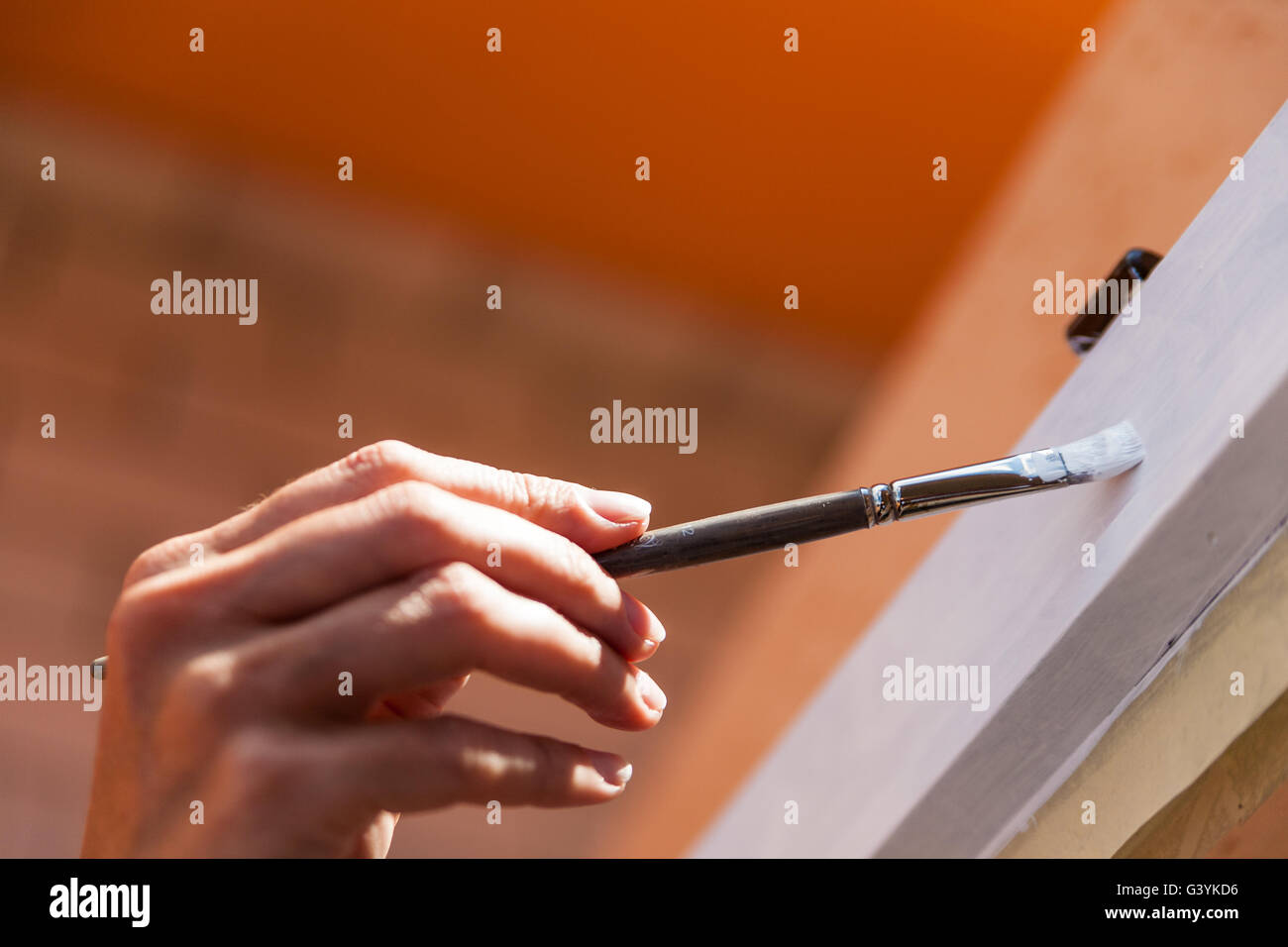 Chiudere fino a portata di mano della persona che entra in contatto di porta in legno o armadio con pennello e vernice bianca Foto Stock