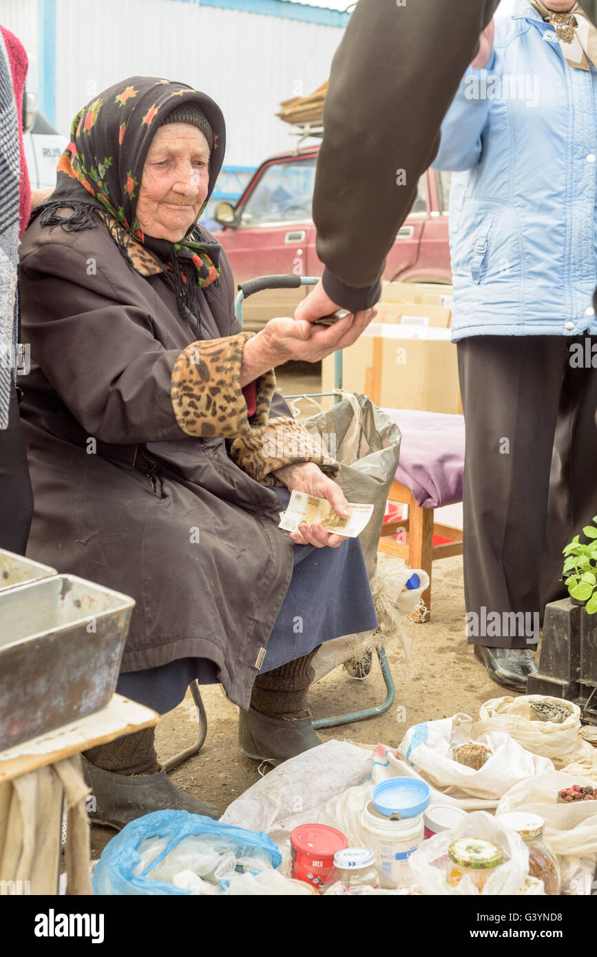 Una vecchia donna russa seduto vende sementi le cipolle a un mercato locale popolare in Russia Foto Stock