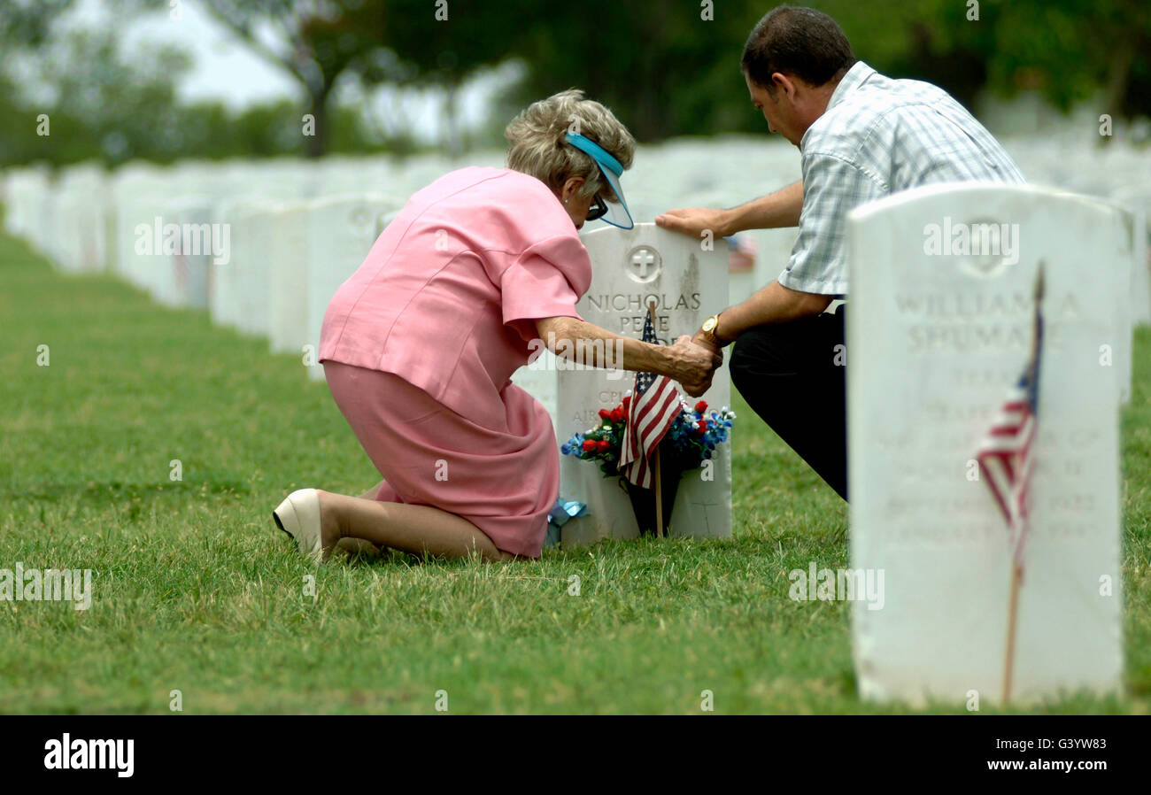 Una madre e suo figlio tenere mani e pregare in un luogo di sepoltura. Foto Stock
