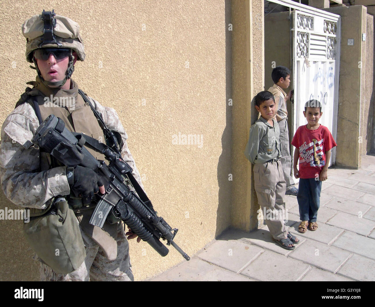 Un gruppo di bambini iracheni osservare un U.S. Marine armato con un: 5,56mm M16A2 fucile. Foto Stock