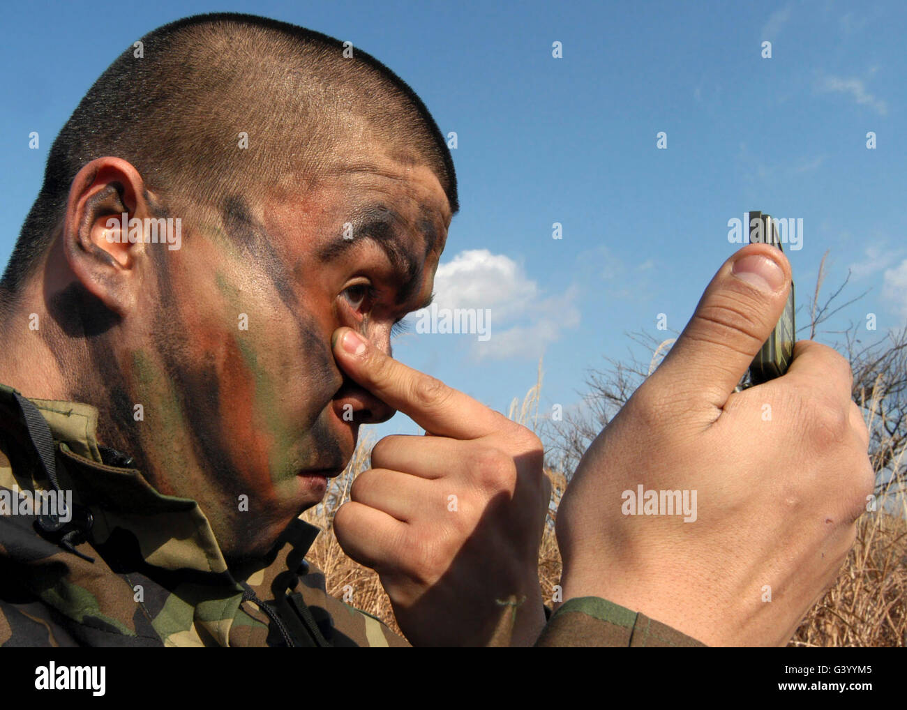 Un soldato di applicazione vernice faccia prima di iniziare le operazioni di aria trimestrale Base Defense Training, Misawa combatté Air Base, Giappone. Foto Stock