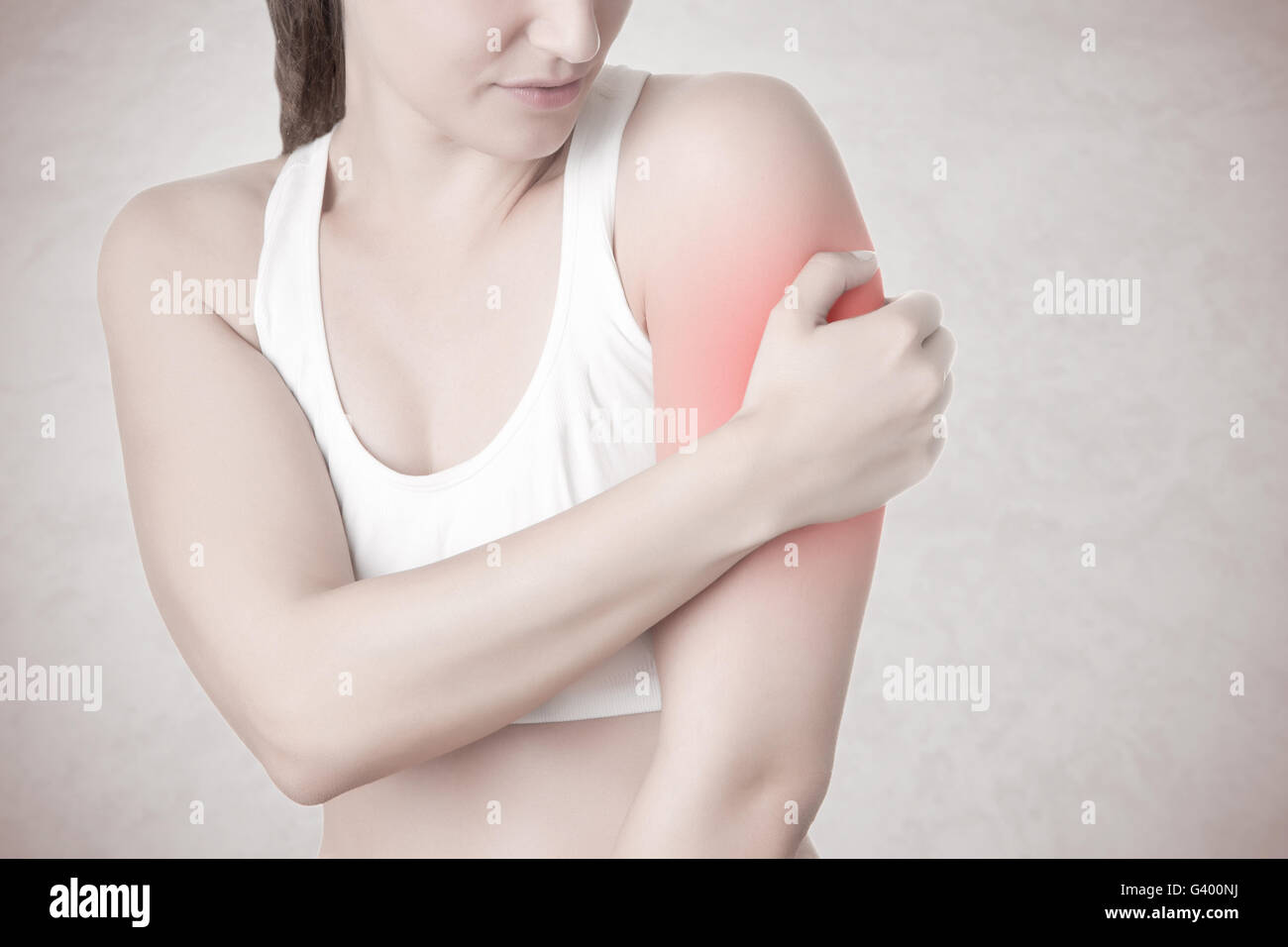 Femmina con il dolore nel suo braccio, isolato in uno sfondo grigio Foto Stock