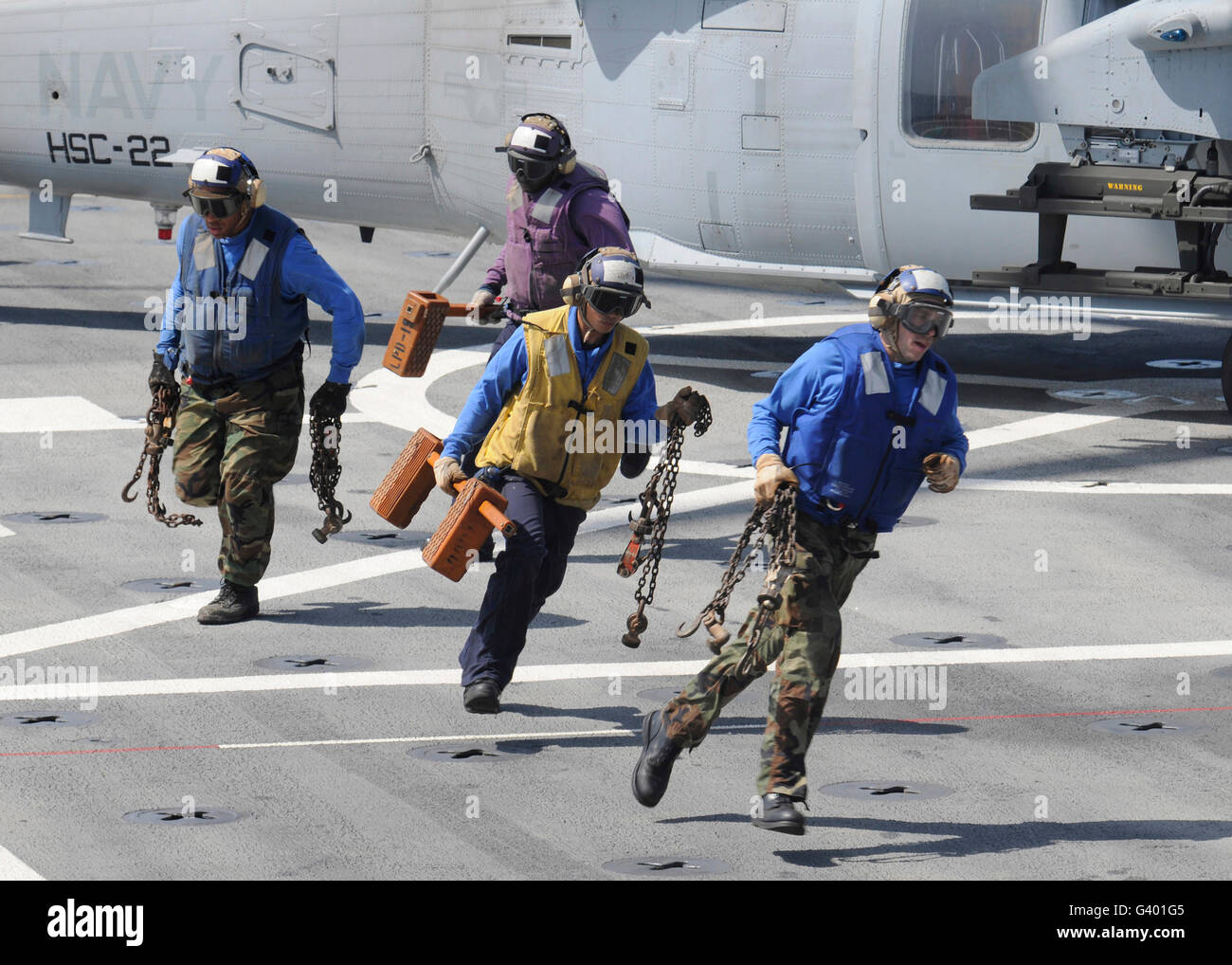 I marinai rimuovere i cunei e catene da un MH-60S Sea Hawk elicottero. Foto Stock