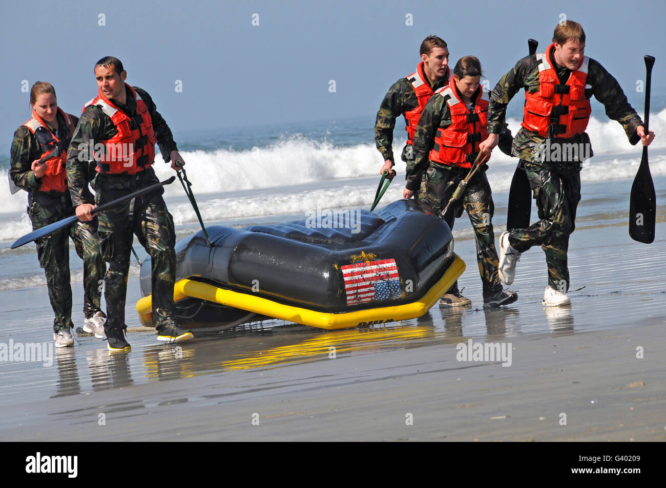 Membri della nazionale statunitense per nuotare Team portano la loro barca a terra dopo il completamento di un passaggio di surf. Foto Stock