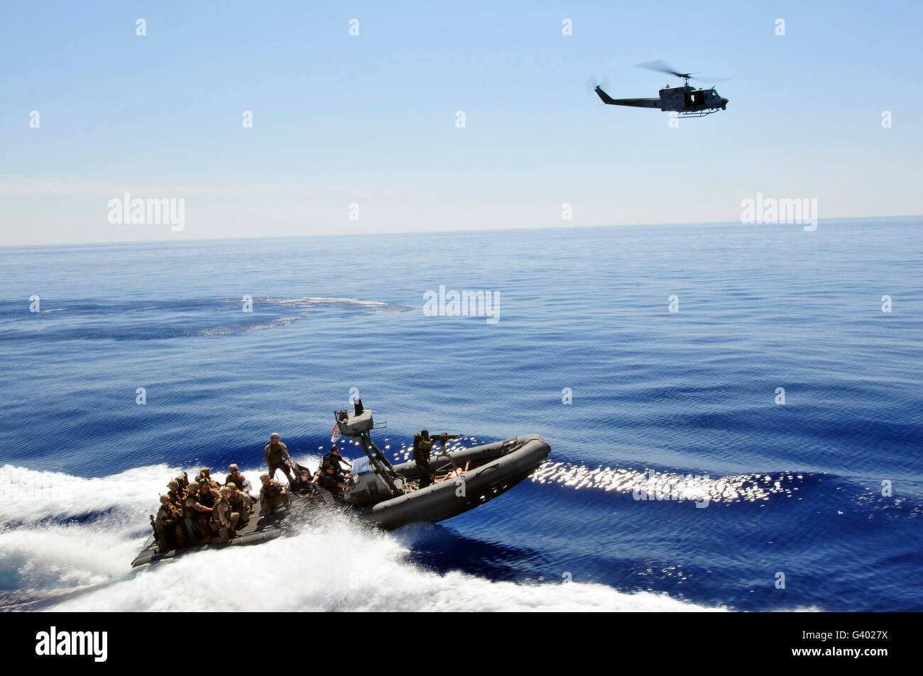 Un U.S. Navy UH-1N Huey elicottero fornisce la copertura per gli Stati Uniti Marines su uno scafo rigido barca gonfiabile. Foto Stock