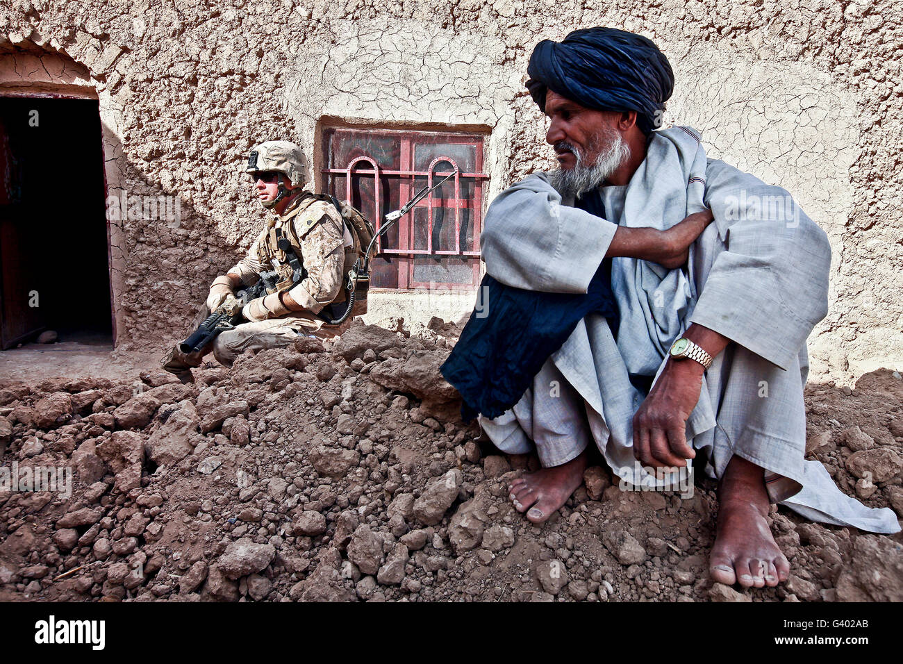 Un soldato raccoglie informazioni da abitanti di un villaggio afgano durante una pattuglia. Foto Stock