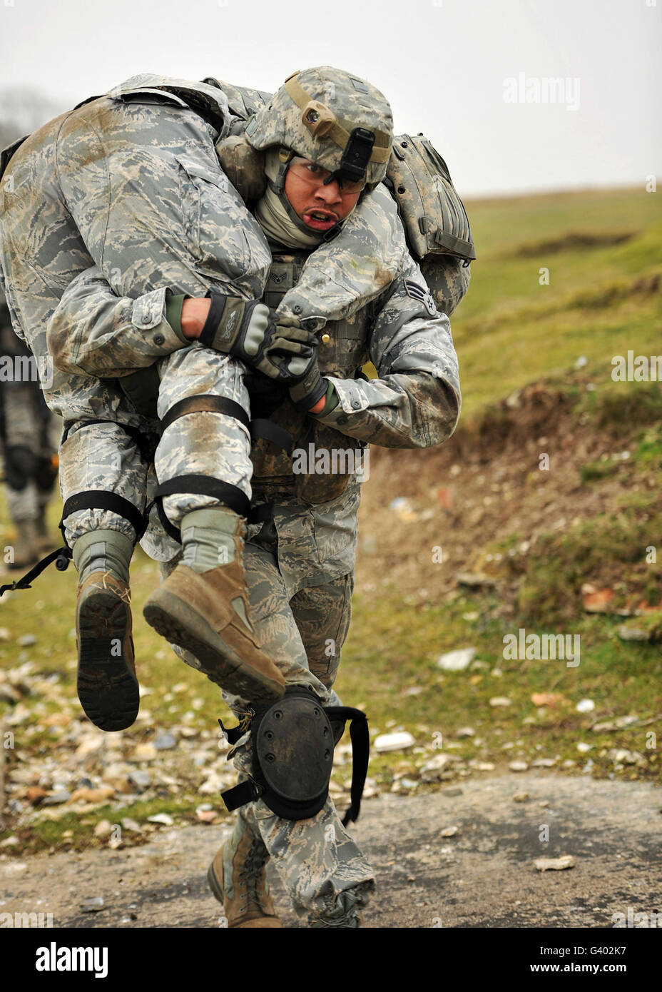 Un soldato trasporta un compagno soldato ferito utilizzando il firemanâ€™s portare la tecnica. Foto Stock