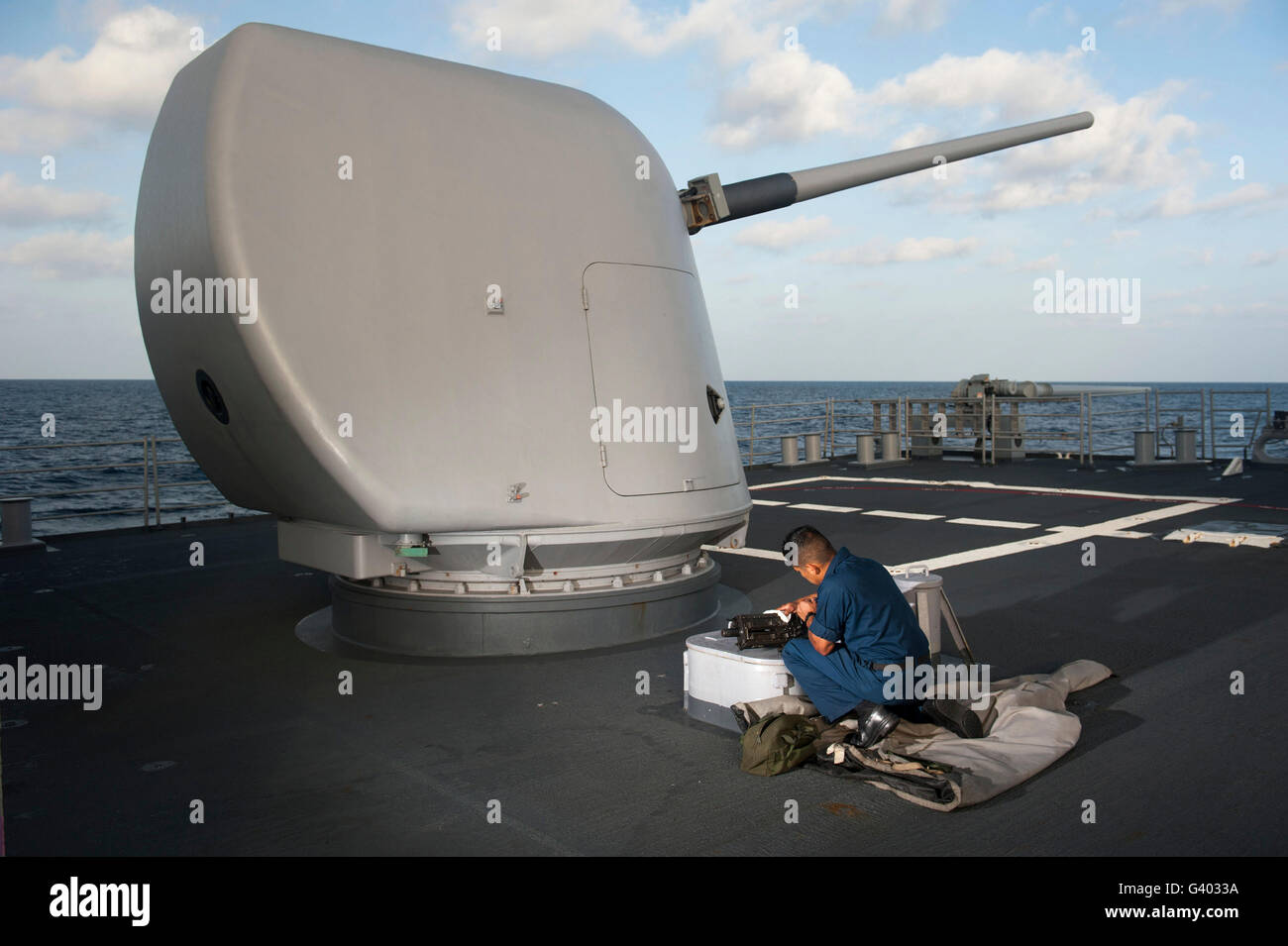Marinaio esegue le operazioni di manutenzione su un .calibro 50 mitragliatrice. Foto Stock