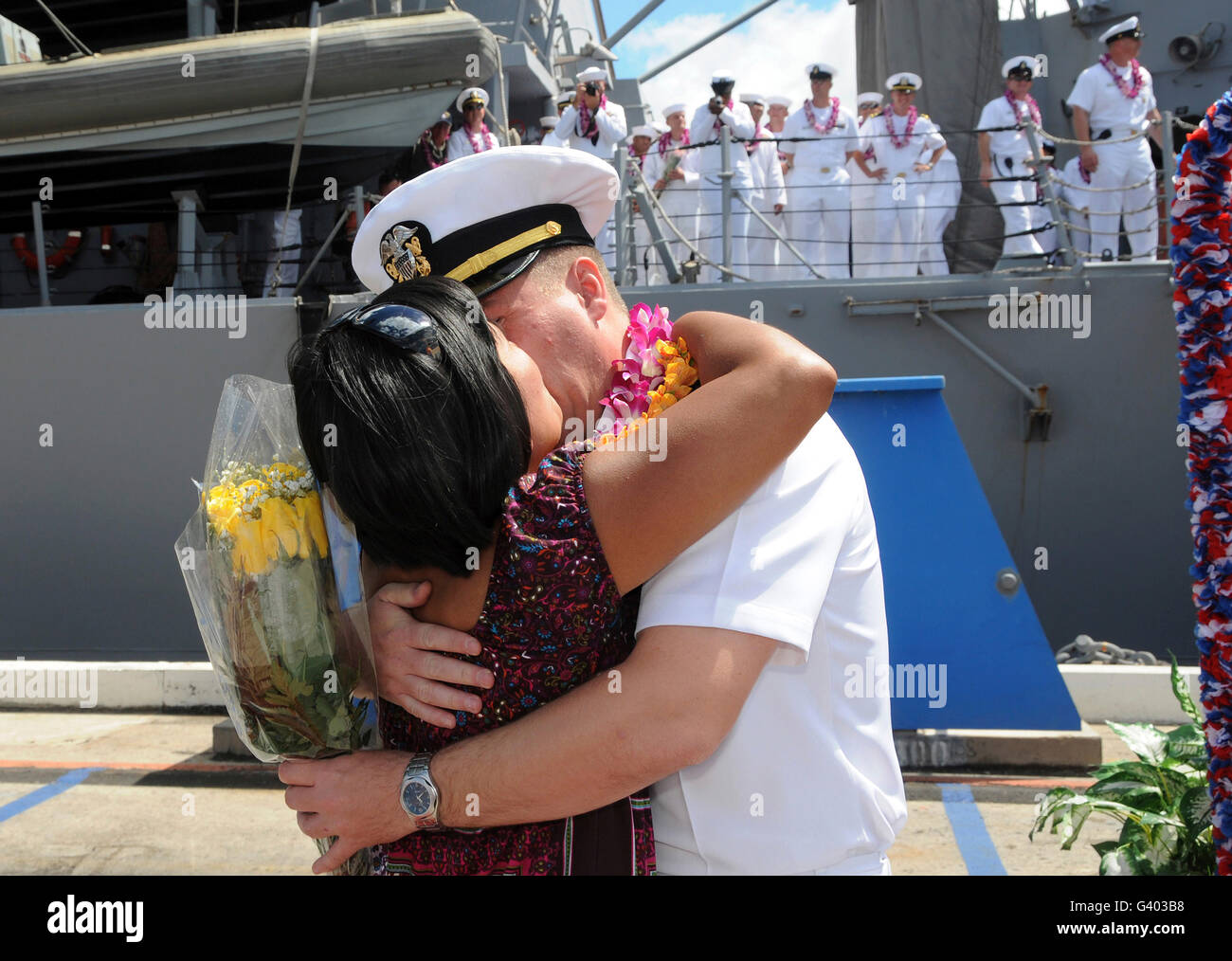 Un U.S. Navy Sailor abbraccia la moglie pierside alla stazione navale Pearl Harbor. Foto Stock