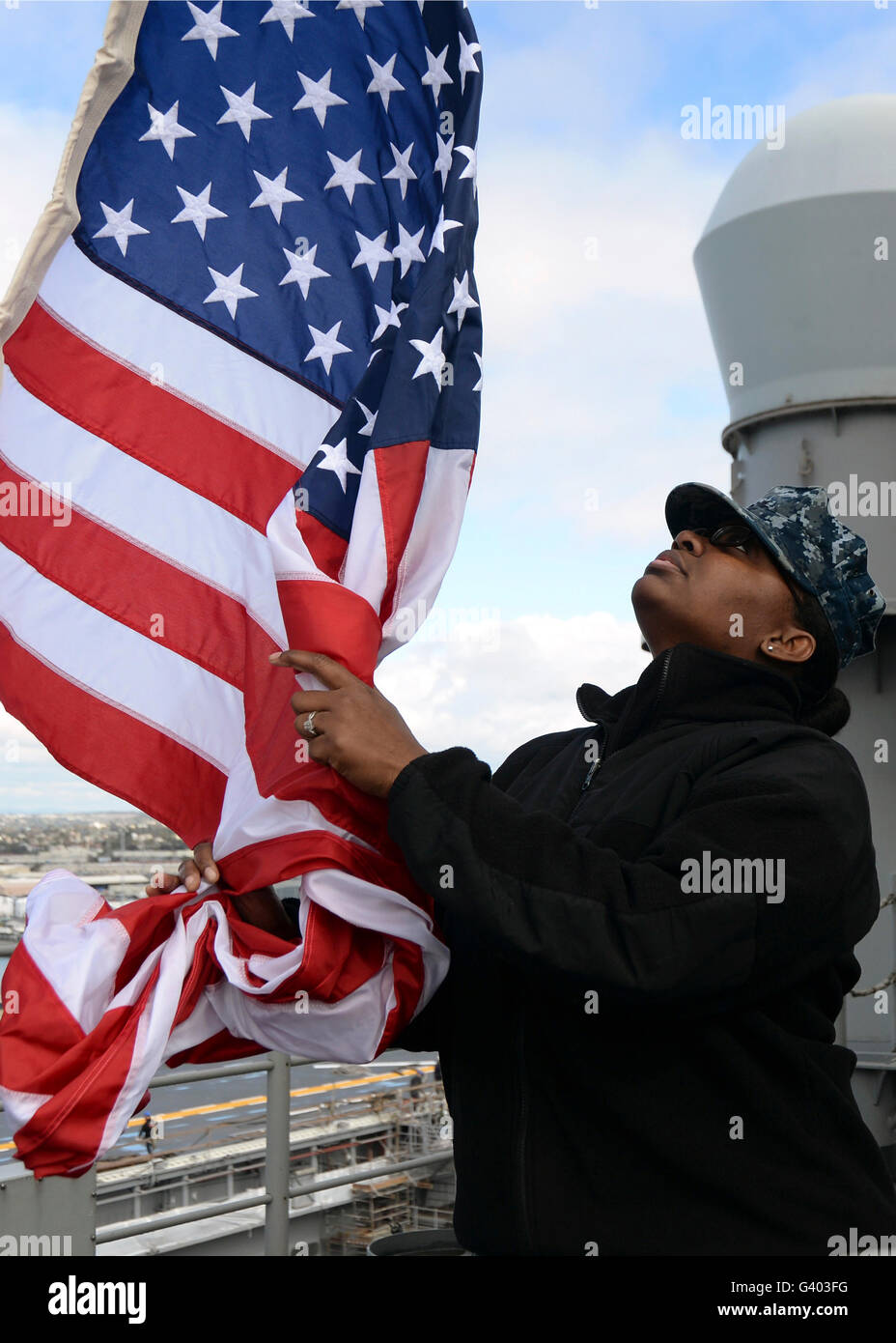 Marinaio solleva il ensign a bordo della USS Makin Island. Foto Stock