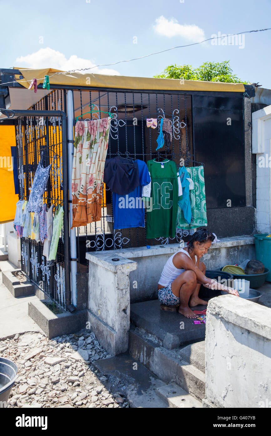 Una donna il lavaggio di se stessa in un cimitero a Manila nelle Filippine Foto Stock