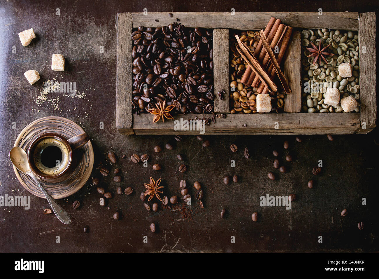 Verde e marrone e non torrefatto Caffè decaffeinato e nero caffè torrefatto in grani con spezie e zucchero nella vecchia scatola di legno e la tazza di ceramica di fresco Foto Stock