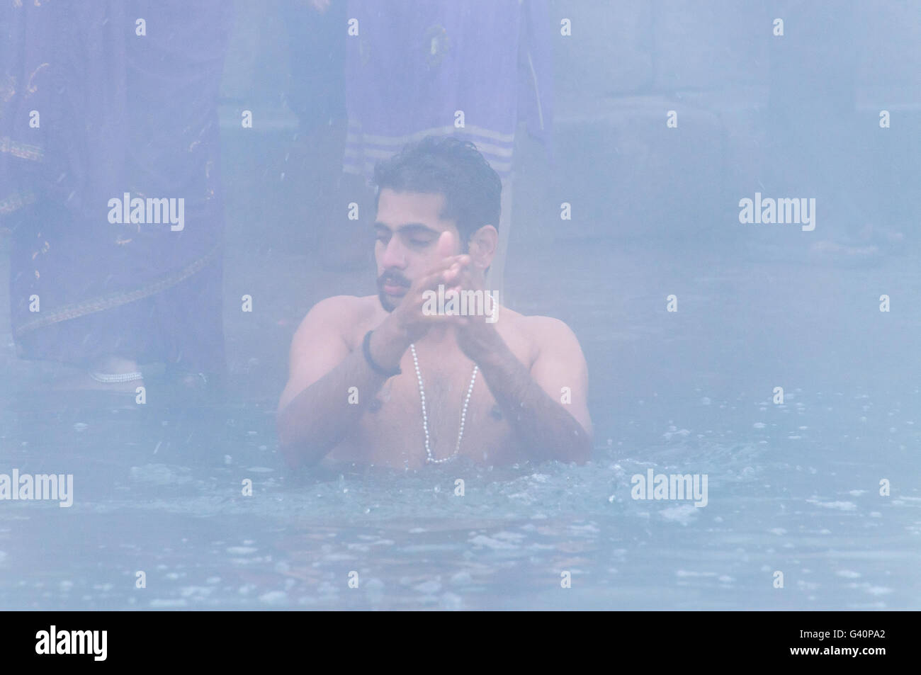 Non identificato uomo indiano prendere santo bagno nel fiume Gange a nebbia fredda mattinata d'inverno. Varanasi Foto Stock