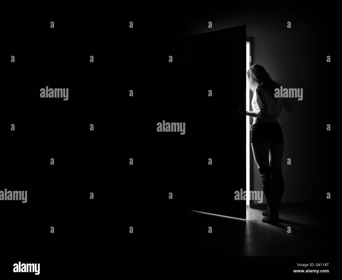 Donna entra per spazio bianco dal buio, immagine monocromatica con copyspace Foto Stock