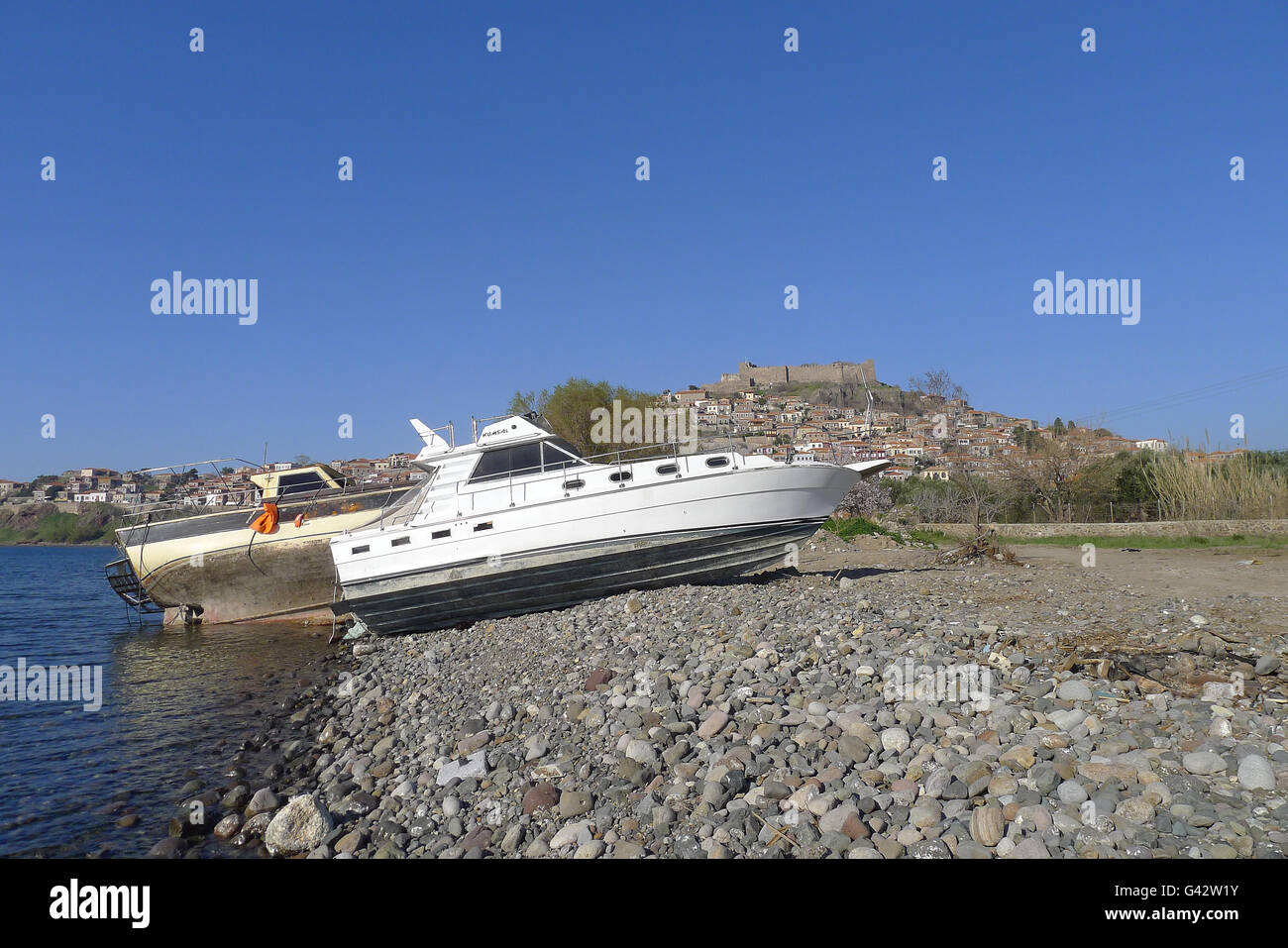 Barca a sinistra dai rifugiati con Castello Molivos in background, Lesbo Grecia Foto Stock