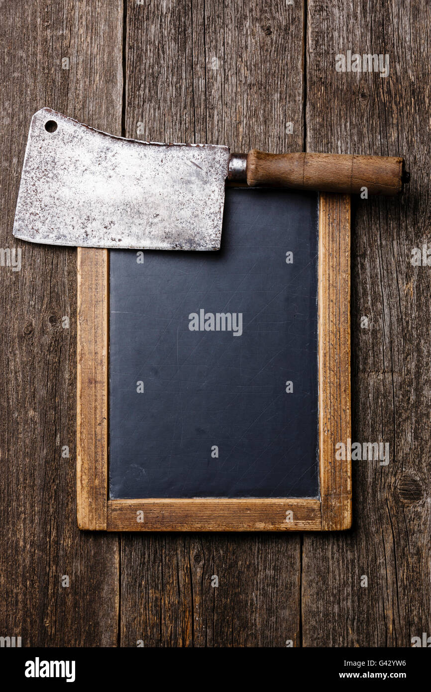 Ardesia Vintage chalk board e Butcher carne cleaver su sfondo di legno Foto Stock