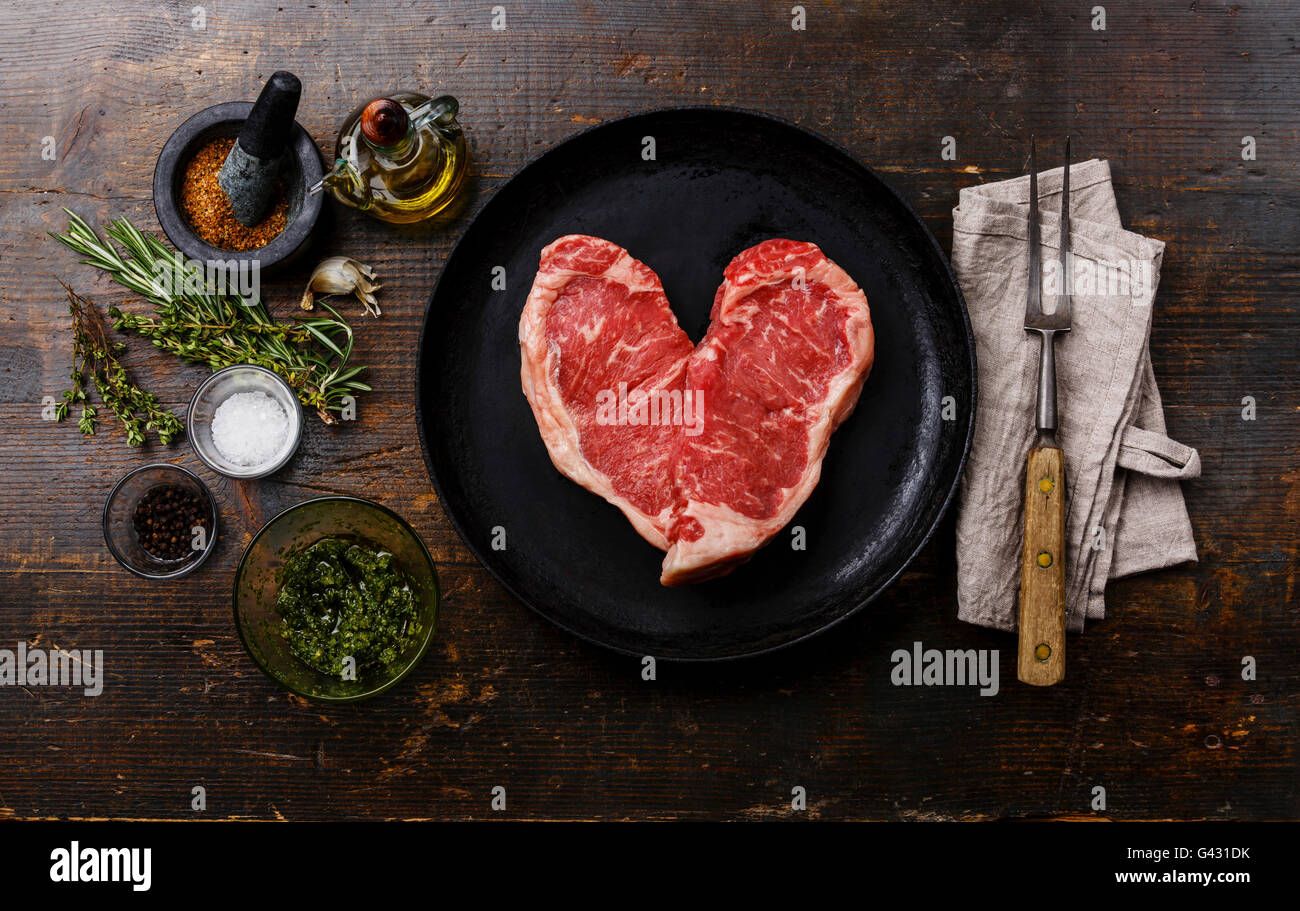 Forma di cuore crudo fresco bistecca di carne controfiletto per due con ingredienti in padella Foto Stock