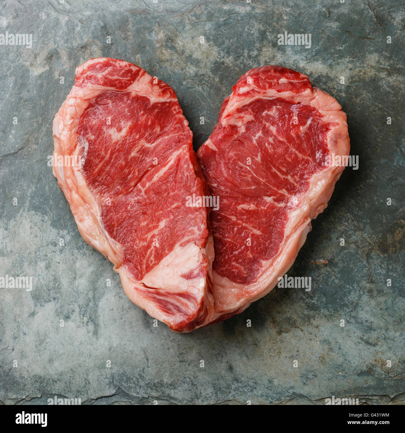 Forma di cuore crudo fresco bistecca di carne controfiletto su pietra ardesia sfondo Foto Stock