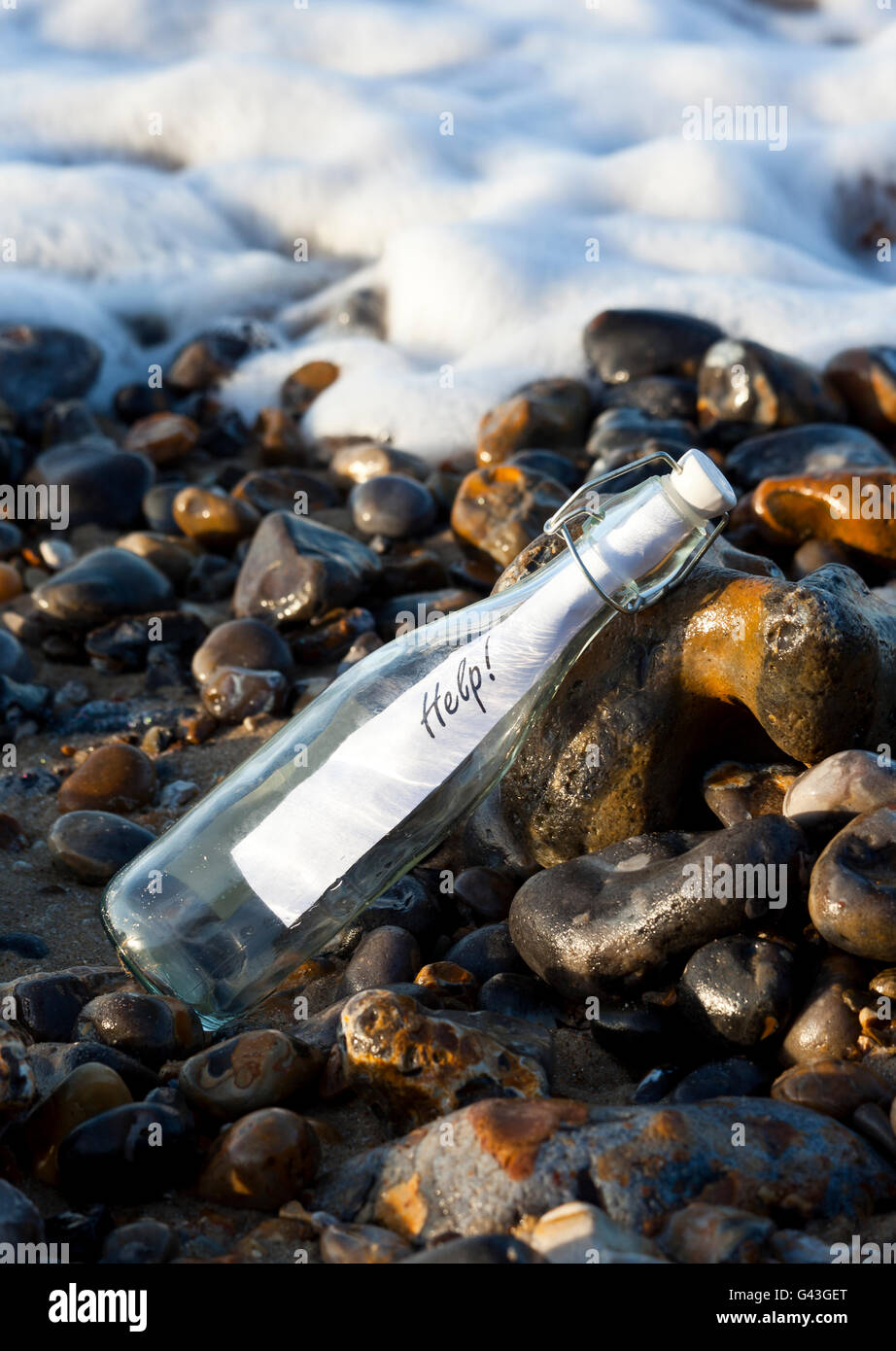 Un messaggio di aiuto in una bottiglia lavato fino su un litorale Foto Stock
