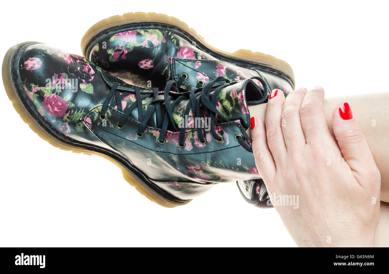 Stile militare stivali con fiori di decorazione su un mani con polis chiodi rossi Foto Stock