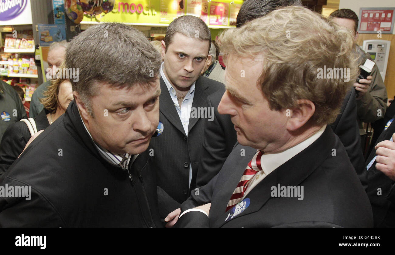 Fine Gael leader Enda Kenny Peaks al tassista Frank Byrne su una tela finale al centro commerciale Donaghmede di Dublino. Foto Stock