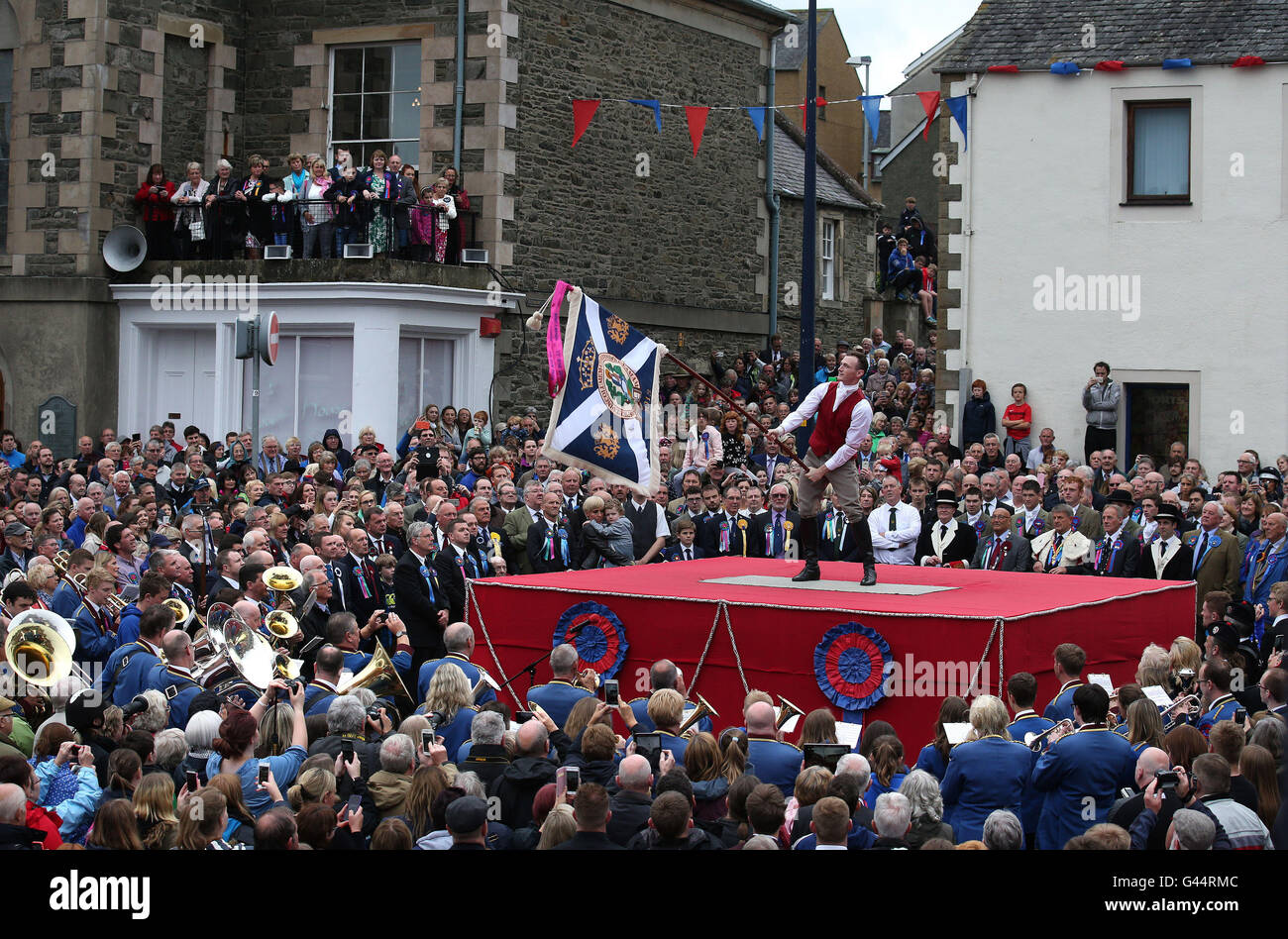 Royal Alfiere Rory J. monaci onde i burgh bandiera durante una cerimonia in Selkirk mercato del luogo durante il Selkirk Equitazione comune, una secolare tradizione nel royal burgh in Scottish Borders. Foto Stock
