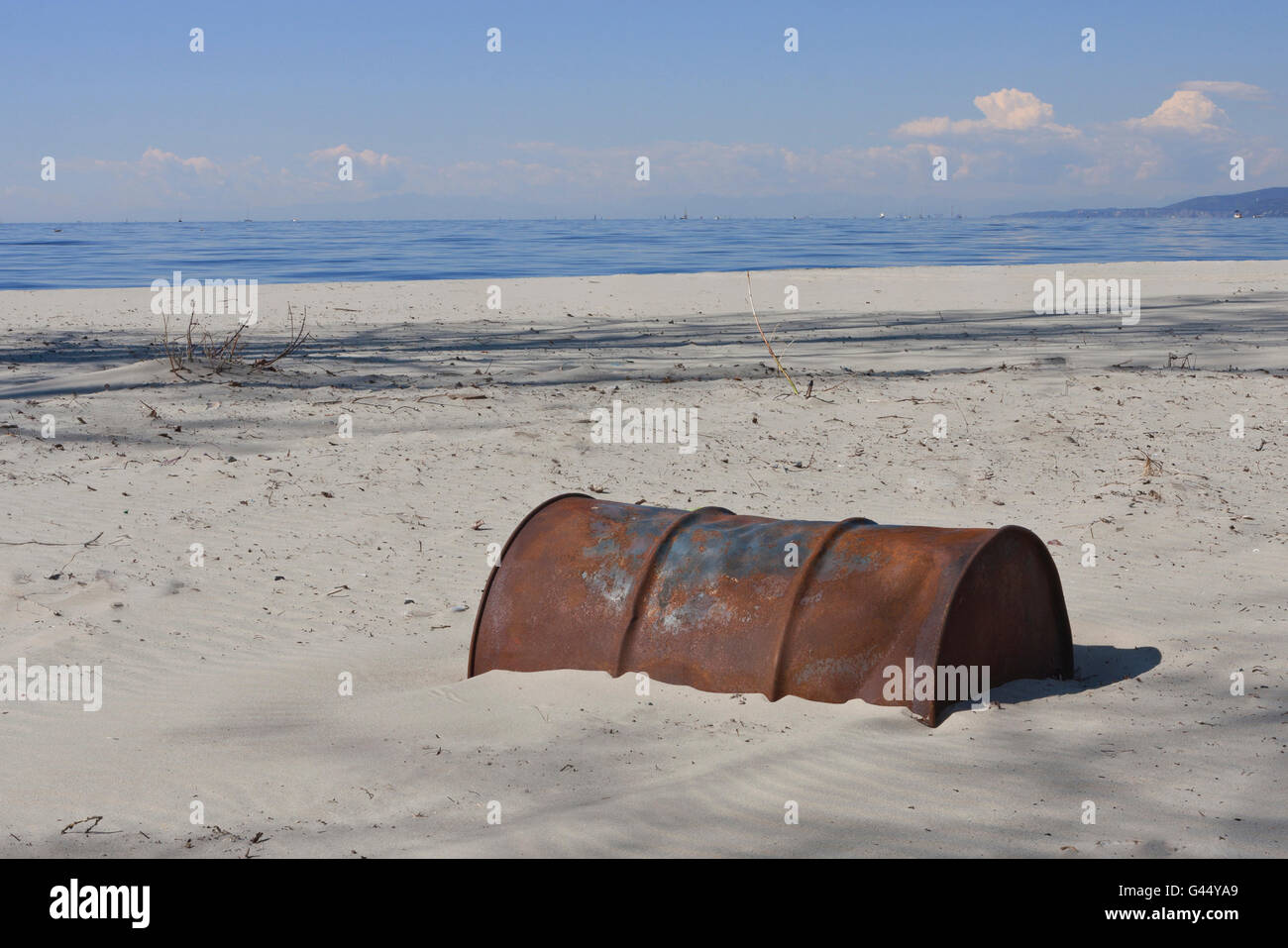 Vecchio arrugginito barile di petrolio sepolto nella sabbia fine di età olio Foto Stock