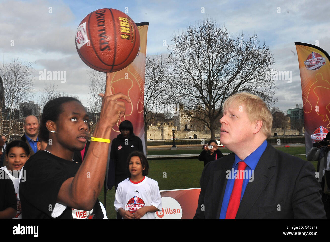 Il sindaco di Londra Boris Johnson impara le abilità di basket da Malcolm Jones, 16 anni, dei Merton Hawks in una fotocellula per lanciare la settimana della pallacanestro NBA al Potters Fields Park, Londra. Foto Stock
