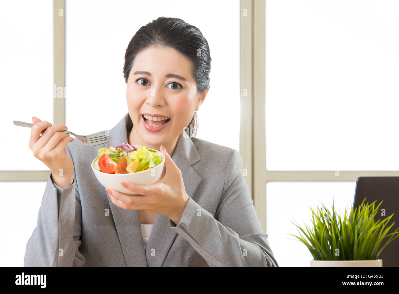 Giovani asiatici imprenditrice godendo di una sana insalata in ufficio Foto Stock
