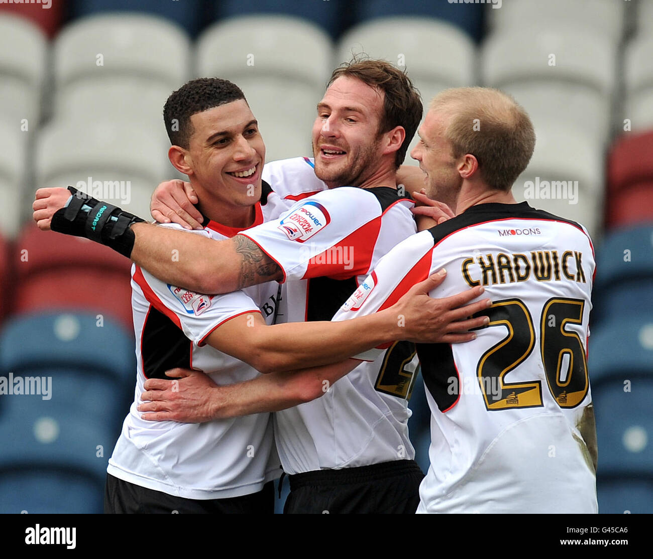 Daniel Powell di Milton Keynes Dons (a sinistra) si congratula per il punteggio Il loro secondo obiettivo di Peter Leven e Luke Chadwick Foto Stock