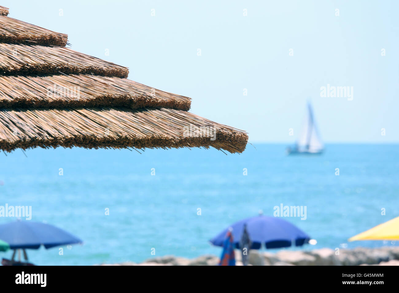 Spiaggia con ombrelloni realizzato con bambù e paglia nel lussuoso resort Foto Stock