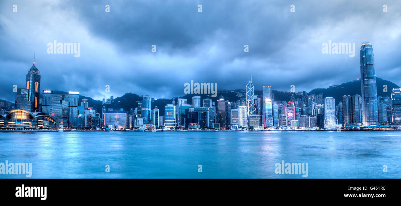 Ampio angolo di vista della skyline di Hong Kong sul Victoria Harbour presi al blue ora dopo il tramonto. Vista dal centro cittadino di Tsim Sha Tsui Foto Stock