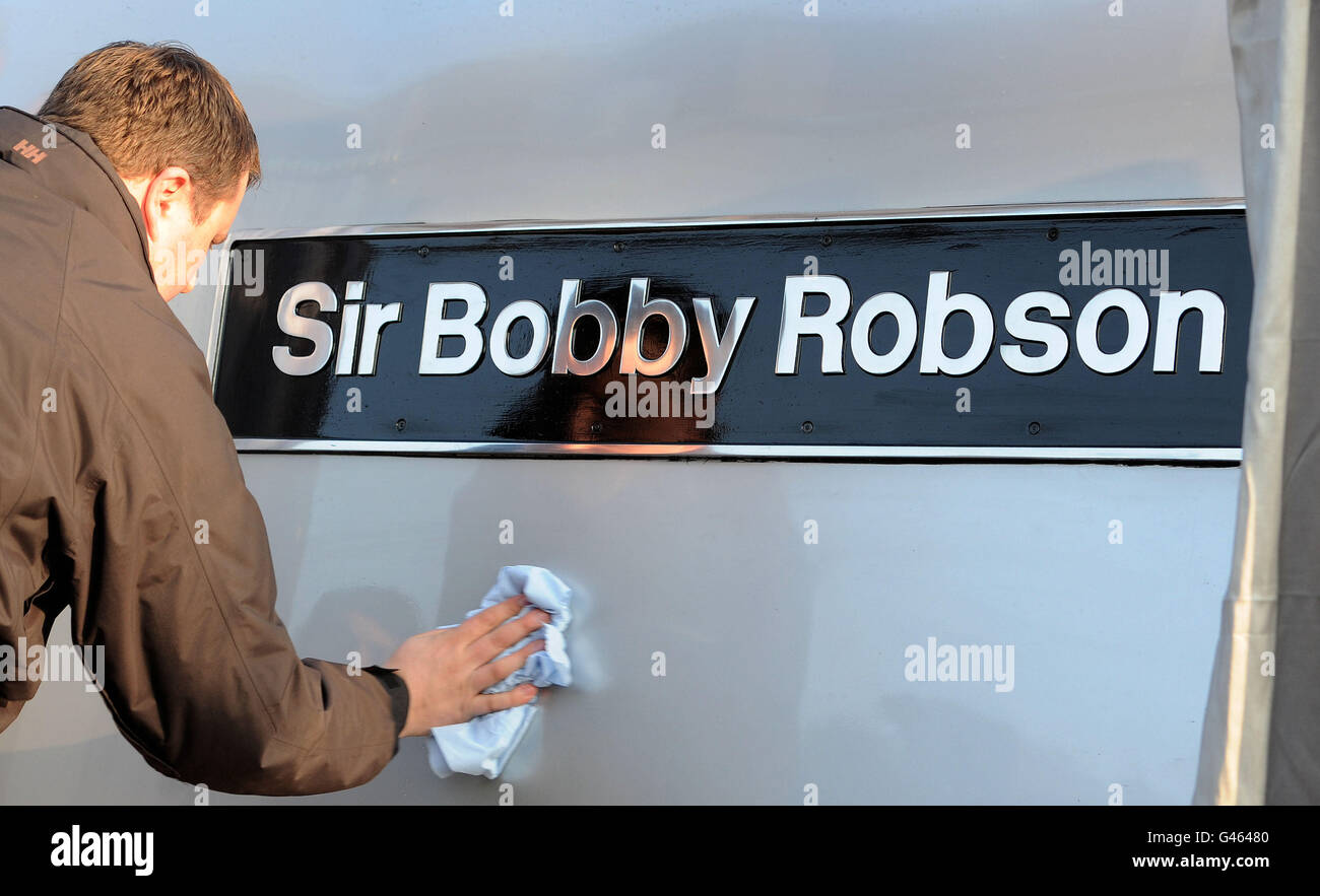 Un uomo pulisce la targa del nome alla presentazione della locomotiva Sir Bobby Robson alla stazione di Newcastle. Foto Stock