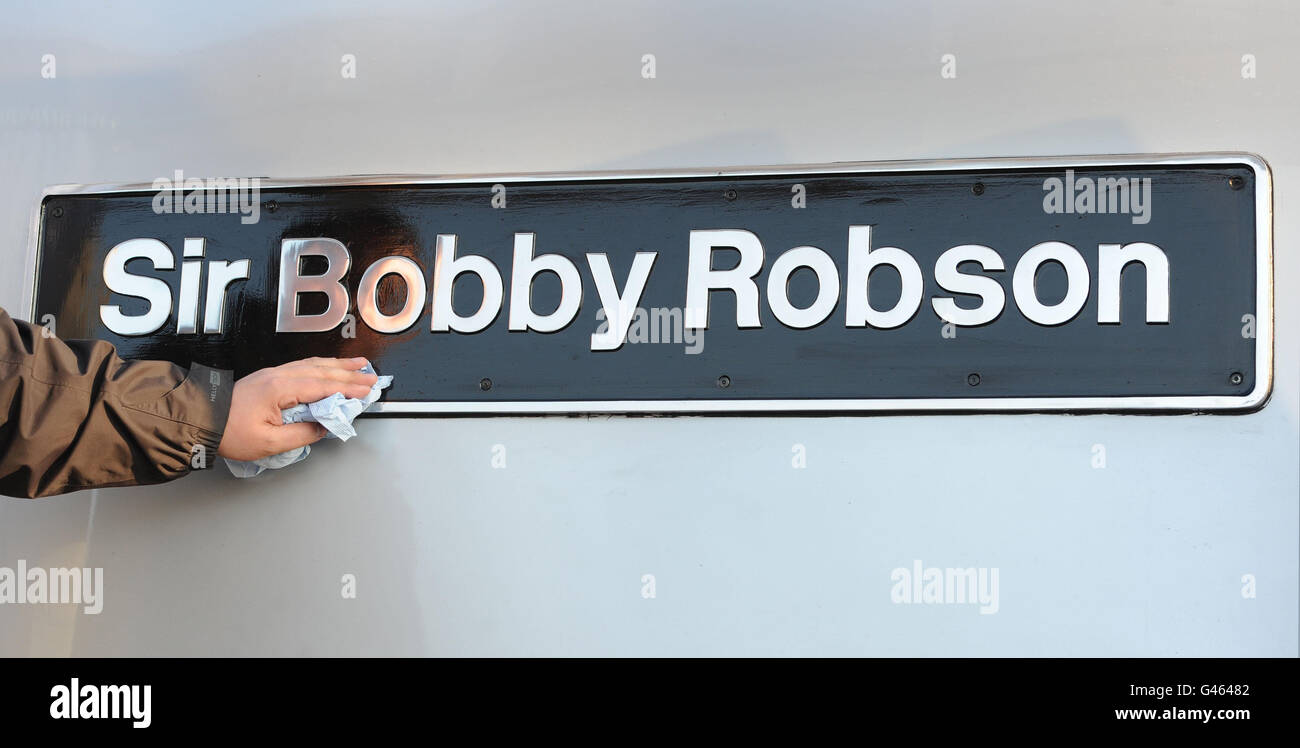 Un uomo pulisce la targa del nome alla presentazione della locomotiva Sir Bobby Robson alla stazione di Newcastle. Foto Stock