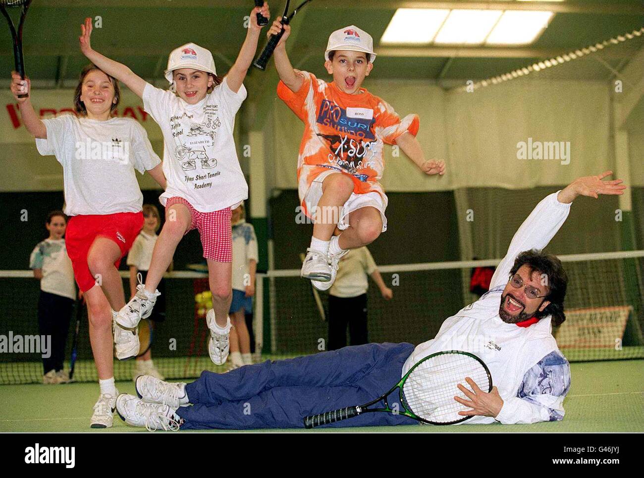 Sir Cliff Richard ha preso tempo dal gioco 'Heathcliff' per aiutare nell'assestamento di ventidue giovani giocatori di tennis in erba al David Lloyd Club, Raynes Park, Surey, ieri (sabato), per lo sviluppo Trust. Nella foto (L-R) sono Abigail Condon di Surrey, Elizabeth Steel di East Yorkshire e Ross Maund di Hampshire. PA. Foto Stock