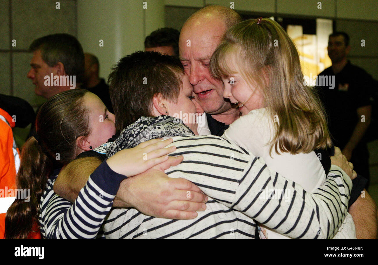 Neil Pickersgill di Manchester ottiene un abbraccio da sua moglie Mandy e figlie Emmy, a sinistra, e Lucy, a destra, come fa la sua strada di ritorno attraverso il Terminal 2 arrivi all'aeroporto di Manchester con altri ufficiali di ricerca e salvataggio. Foto Stock