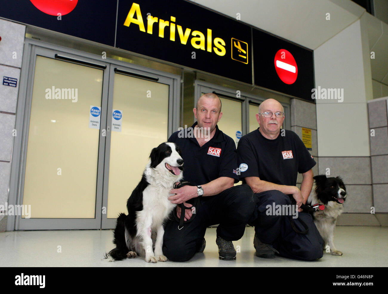 Robin Furniss e il suo cane da ricerca Byron, a destra, e Steve Buckley con Bryn, a sinistra, fanno il loro ritorno attraverso gli arrivi al Terminal 2 all'Aeroporto di Manchester. Foto Stock