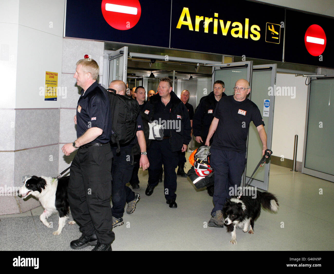 Robin Furniss e il suo cane da ricerca Byron, a destra, fanno il loro ritorno attraverso gli arrivi del Terminal 2 all'aeroporto di Manchester con i compagni di ricerca e di soccorso ufficiali. Foto Stock