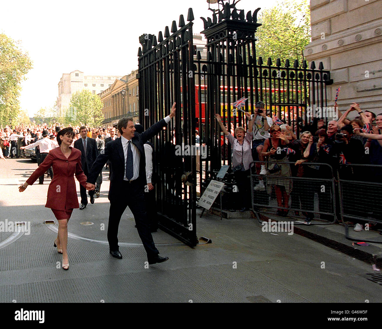 Il nuovo primo ministro Tony Blair e sua moglie Cherie camminano di pari passo verso Downing Street questo pomeriggio (venerdì), mentre la folla di Union Jack si acclama. Il Partito laburista ha vinto le elezioni generali di ieri con una vittoria schiacciante, lasciando i Tory con il loro risultato più povero dal 1832. Foto Stock