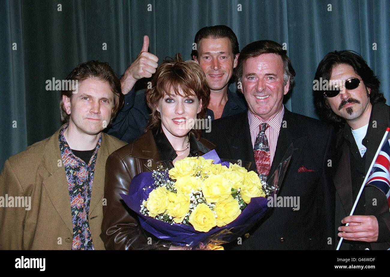 Terry Wogan (2° a destra) aiuta Katrina e le onde Kimberley REW (all'estrema sinistra), Alex Cooper (camicia blu) Katrina (fiori in mano) e vince de la Cruz (all'estrema destra) a festeggiare oggi all'aeroporto di Heathrow (domenica). Katrina e le onde hanno vinto il concorso Eurovisione Song Contest ieri sera con la canzone Love Shine A Light . Foto di David Giles/PA. Vedere la storia di PA SHOWBIZ Eurovisione Foto Stock