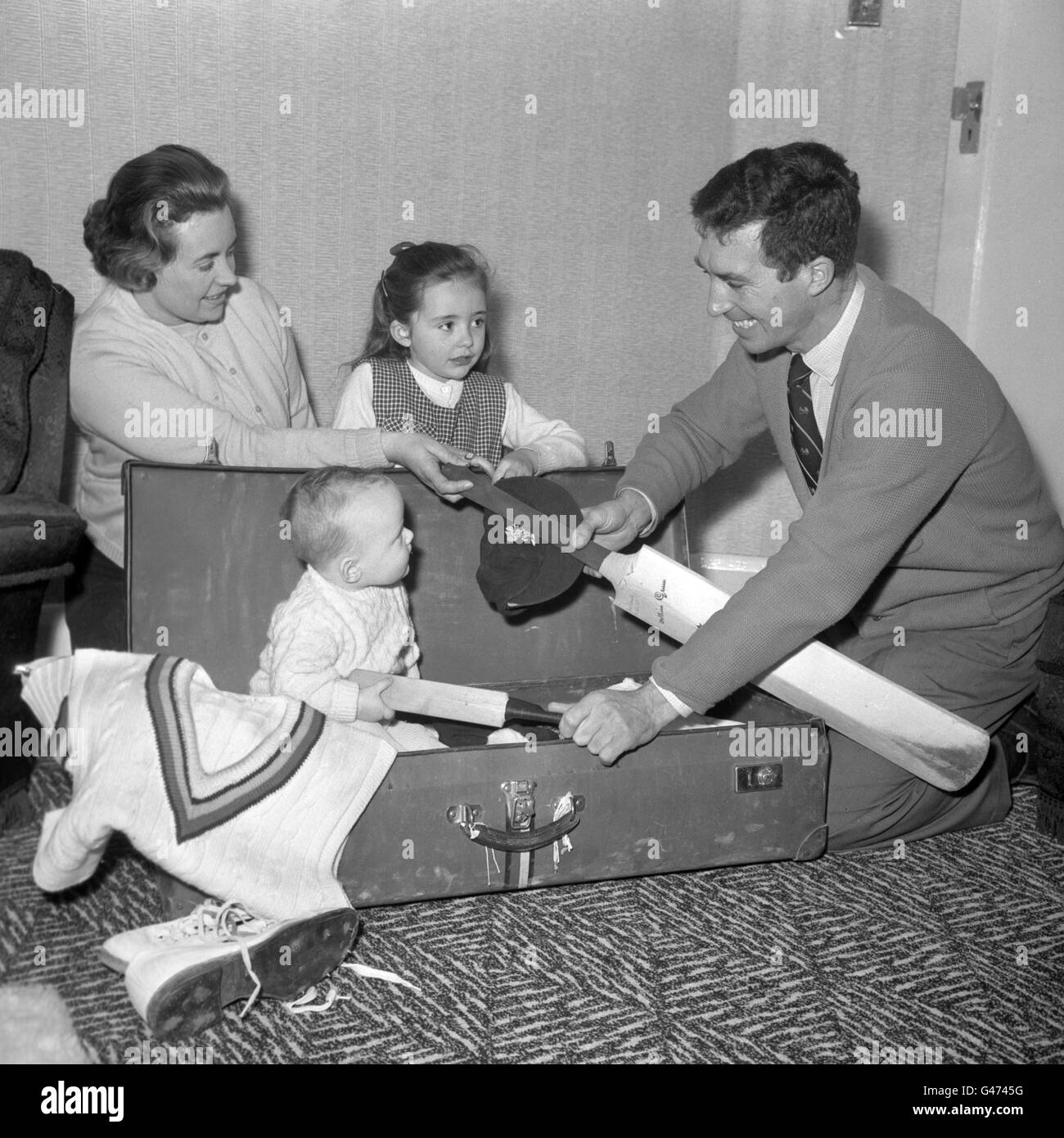 Mark Titmus, nove mesi, offre il suo mazzetto in miniatura, mentre si unisce alla famiglia, aiutando suo padre, Middlesex e il cricketer d Titmus Inghilterra, a fare il pacco a casa per il tour MCC di India e Pakistan. Sono anche raffigurati sua moglie Jean e sua figlia di sei anni Dawn. Foto Stock