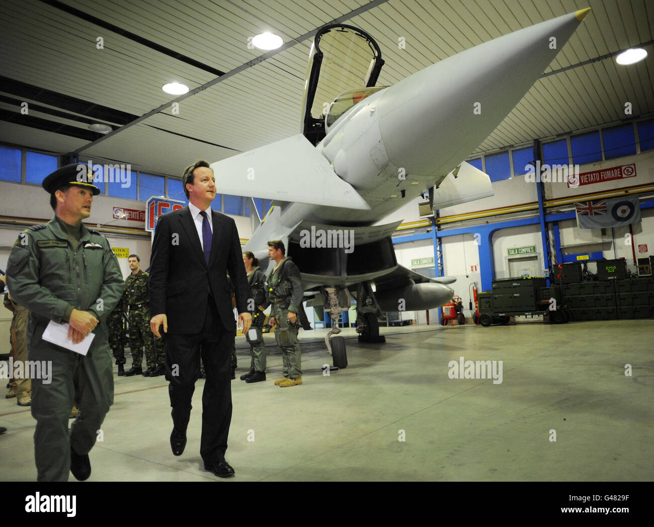 Il primo Ministro David Cameron cammina con il Capitano del Gruppo Sammy Sampson a gioia del Colle, durante una visita a sorpresa alla base aerea italiana del sud Italia per incontrare e ringraziare l'equipaggio di terra e i piloti RAF. Foto Stock