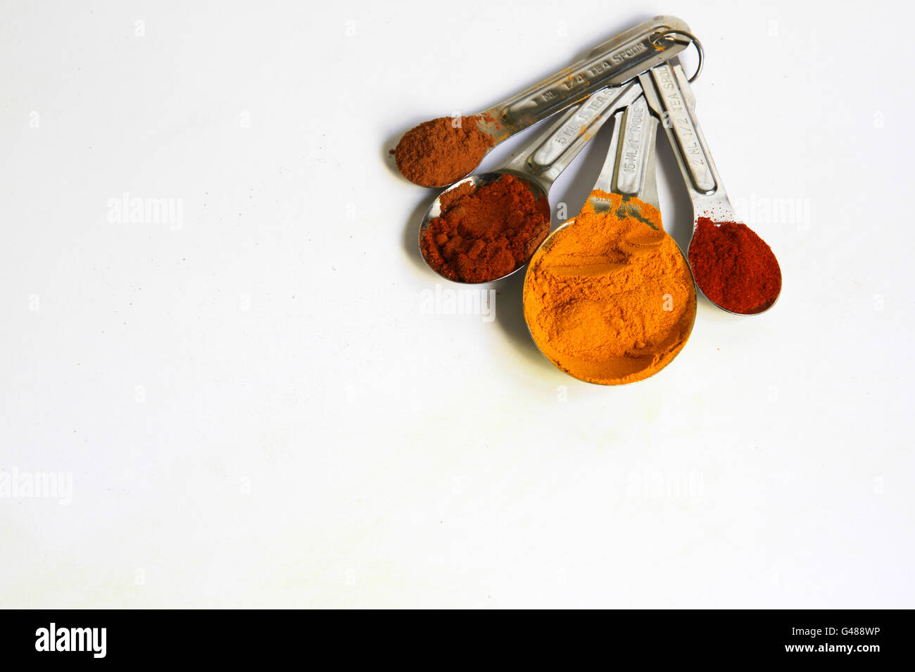 Foto di metallo quattro misurini riempito con spezie colorate isolato su bianco. La curcuma, cannella, pepe di Caienna e paprica in cucchiai Foto Stock Foto di metallo quattro misurini riempito con spezie colorate isolato su bianco. La curcuma, cannella, pepe di Caienna e paprica in cucchiai Foto Stock