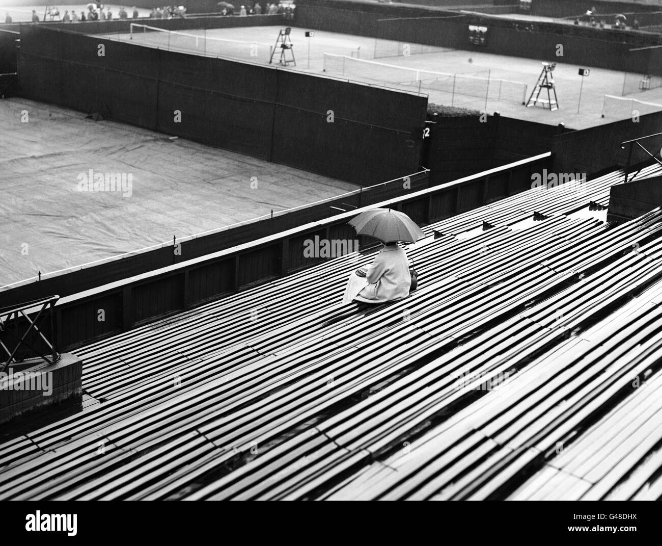 Quando una forte tempesta di pioggia ha spazzato Wimbledon, il gioco si è fermato, i campi sono stati coperti e gli spettatori si sono affrettati a trovare rifugio. Foto Stock