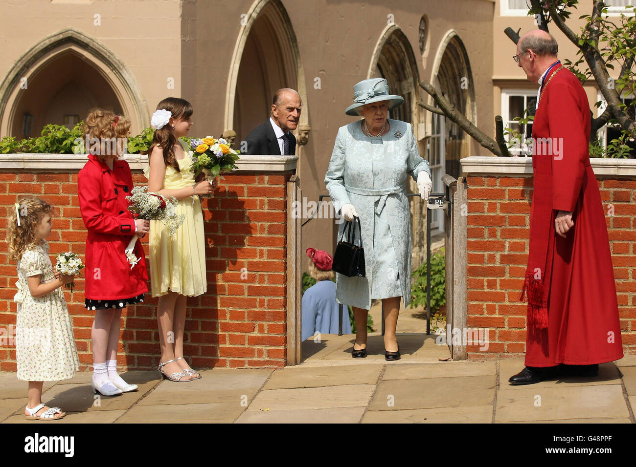 I bambini aspettano con i fiori mentre la regina Elisabetta II e il duca di Edimburgo lasciano il Servizio dei Matini di Pasqua alla Cappella di San Giorgio, Castello di Windsor, come guarda il destro don David Conner, Decano di Windsor. Foto Stock